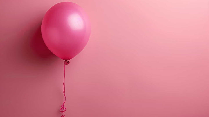 Single pink balloon against a pink background